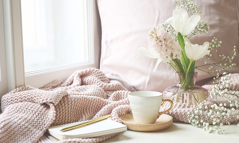 Cup of tea, opened notebook, pink knitted plaid on windowsill. Vintage feminine styled photo, floral composition with tulips, hyacinth and Gypsophila flowers.