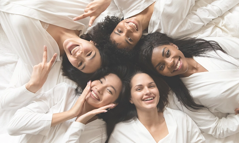 Top view five diverse women in white bathrobes lying in bed smile look at camera feels happy after body treatment, day spa procedures, resort beauty salon satisfied clients, bachelorette party concept