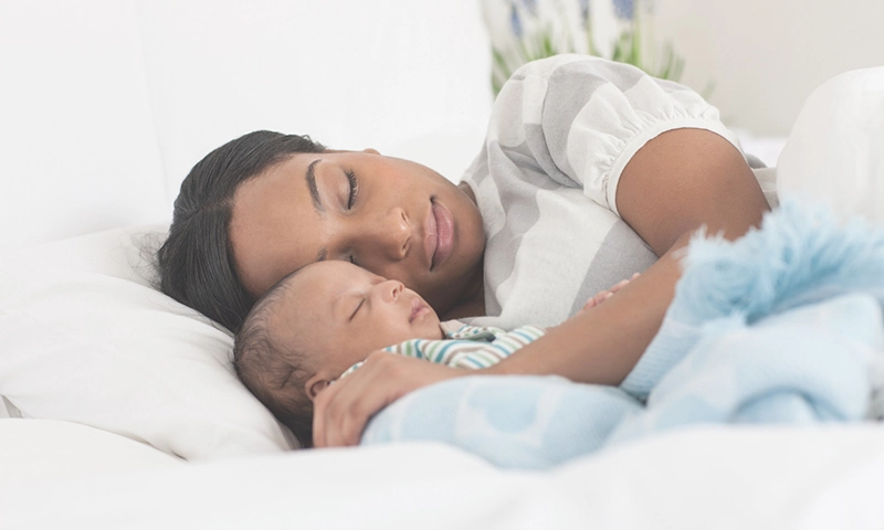woman sleeping next to her baby