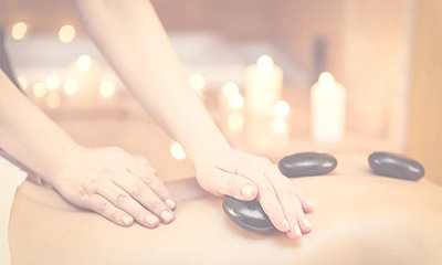 woman's back being massaged with hot stones